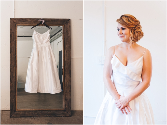 Wedding Dress hanging in front of mirror and bride getting ready at the Fremont Foundry in Seattle. Image captured by Ardita Kola Photography.