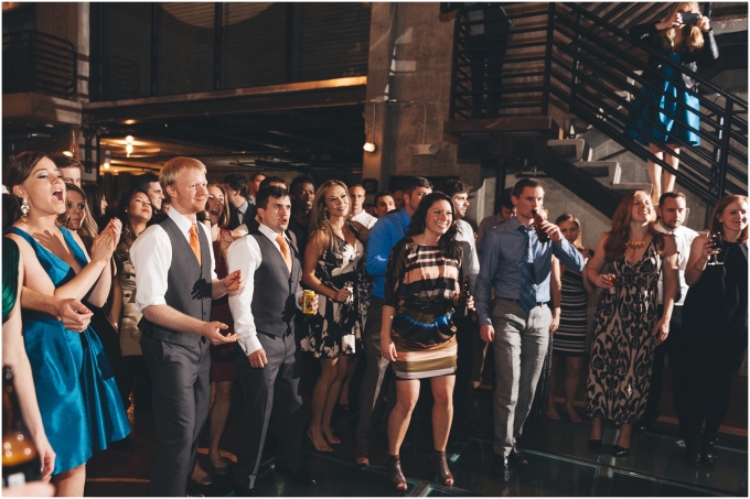 Guests enjoy listening to the Bride singing at her own wedding at the Fremont Foundry in Seattle. Image captured by Ardita Kola Photography.